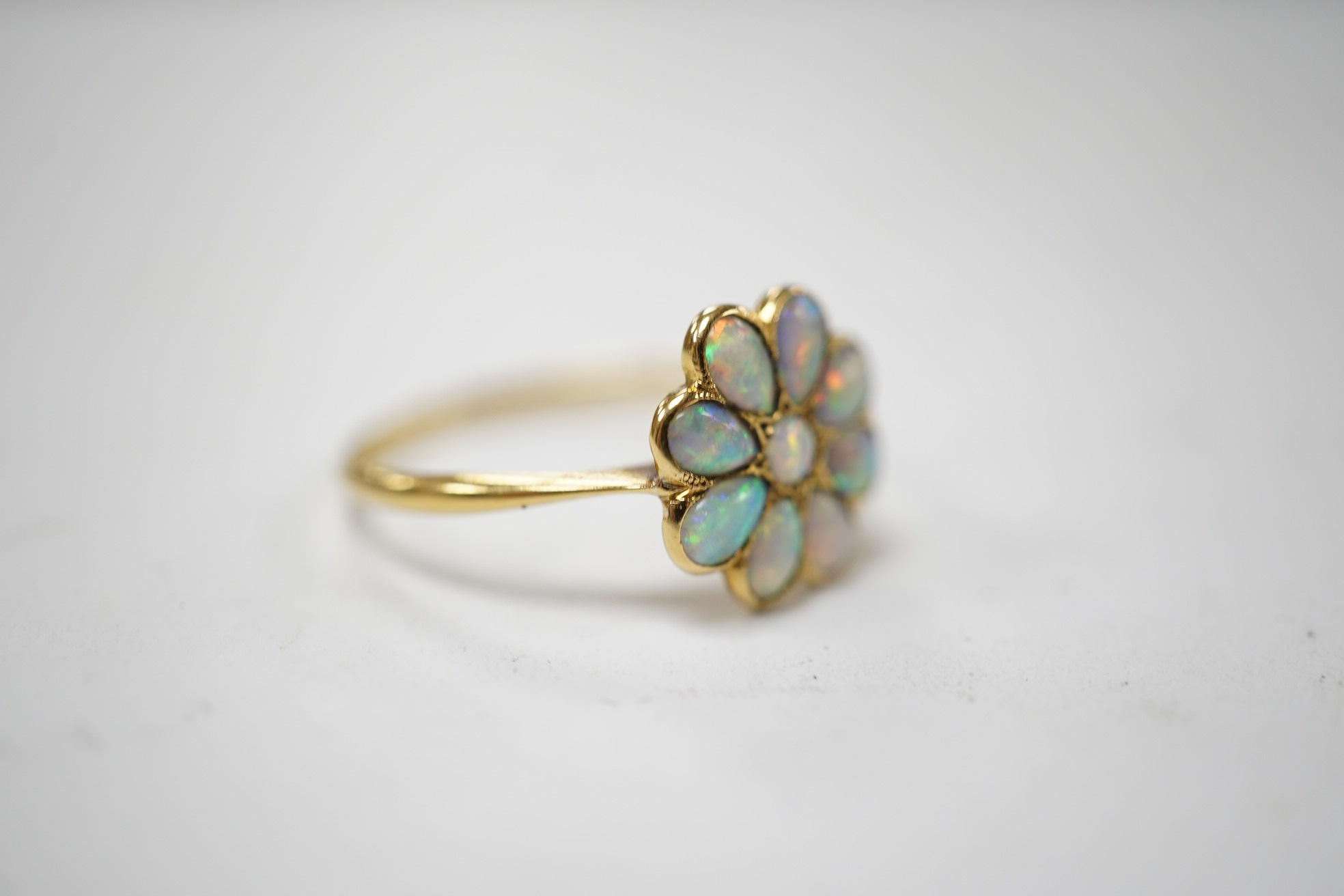 An 18ct and white opal set flower head cluster ring, size N, gross weight 1.7 grams. Condition - poor